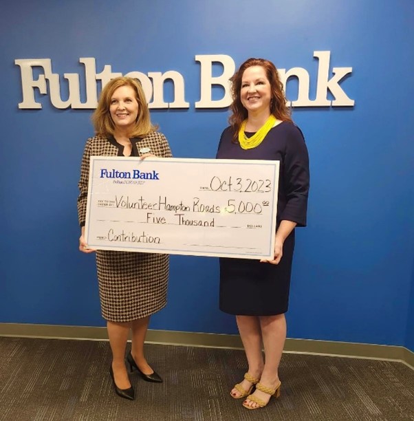 two business women standing with a large check