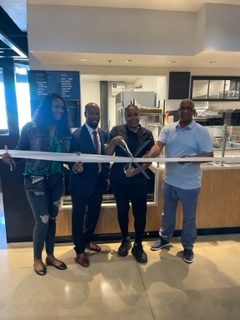 Four people cutting a ribbon to open Sweet Peaz Southern Kitchen